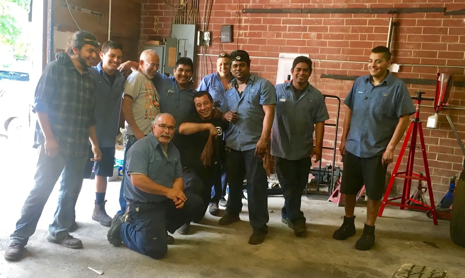 The Transpecialists of Hickory crew — ten technicians in blue work shirts — gathered in the shop in front of a brick wall.
