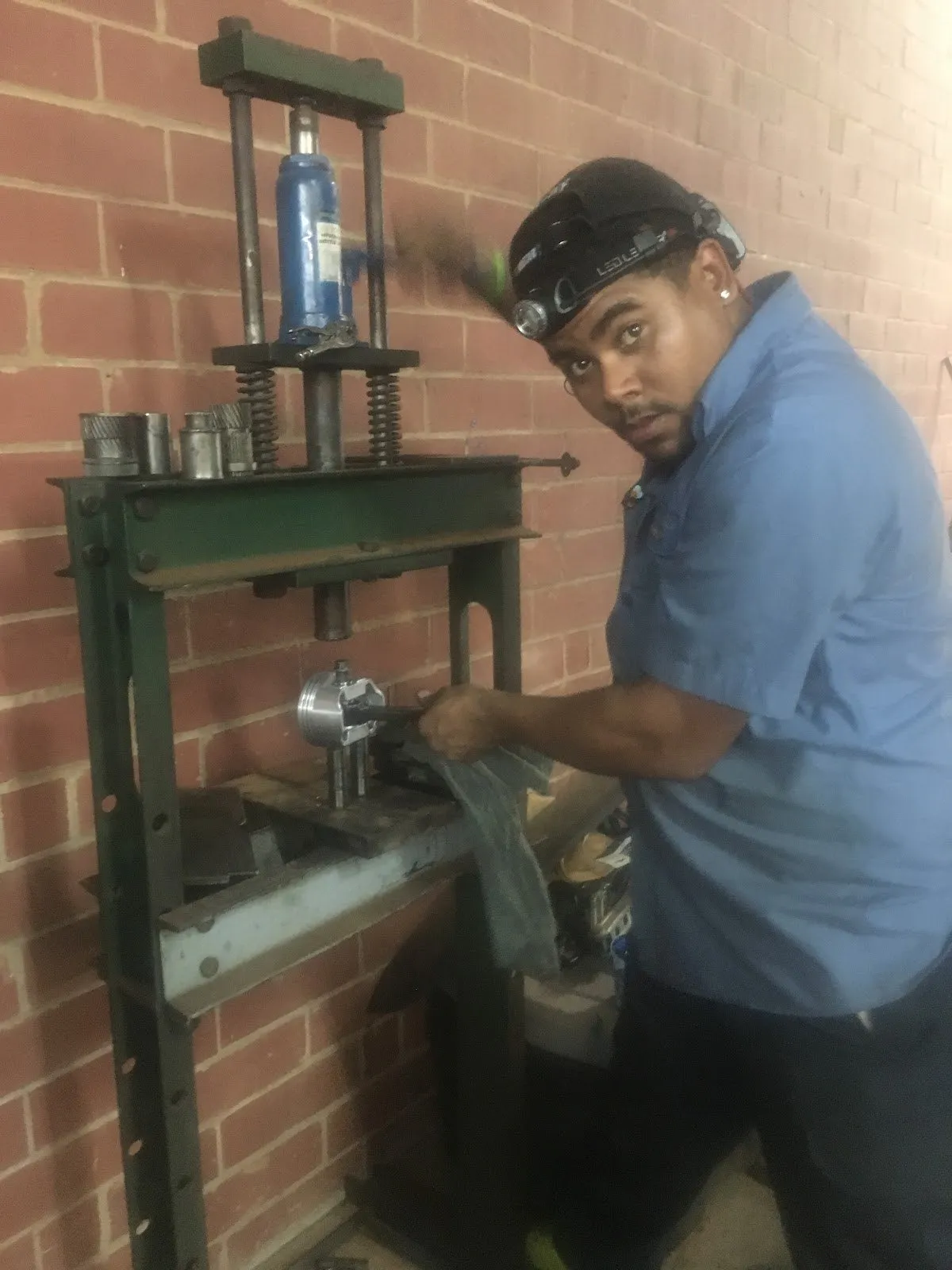 A technician using the shop hydraulic press on a drivetrain component.