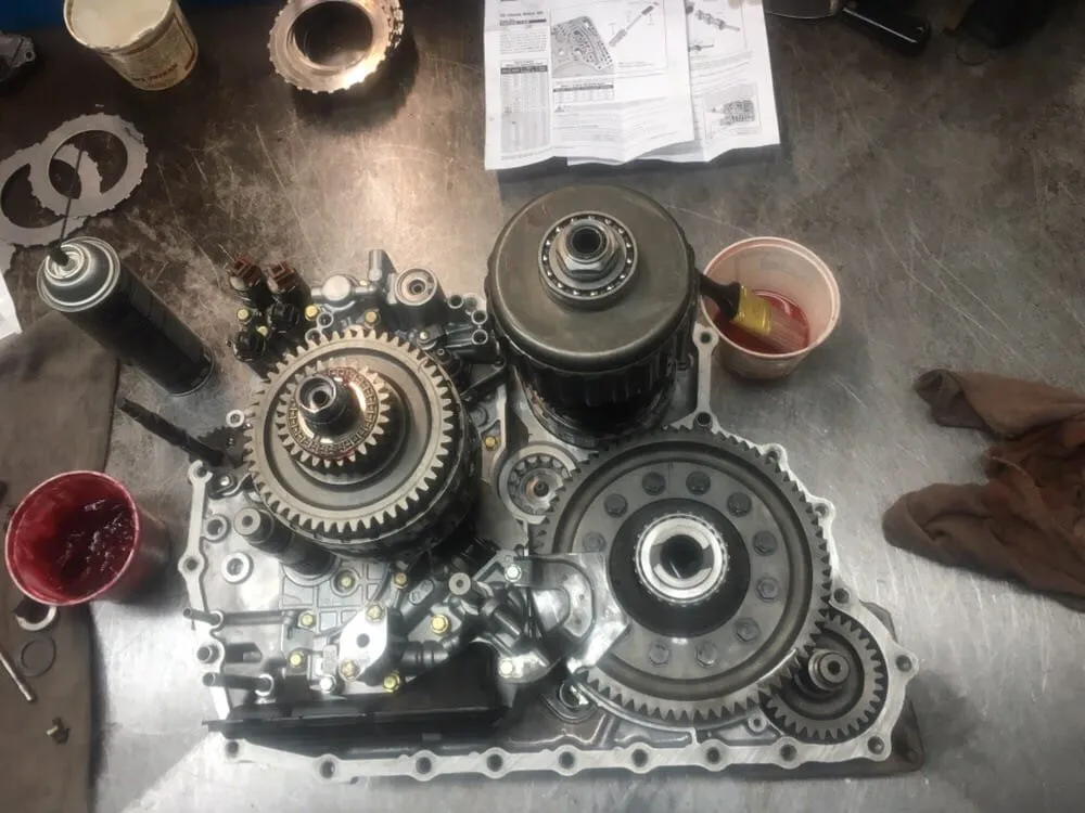 A front-wheel-drive transaxle opened up on the bench with its gear shafts exposed.